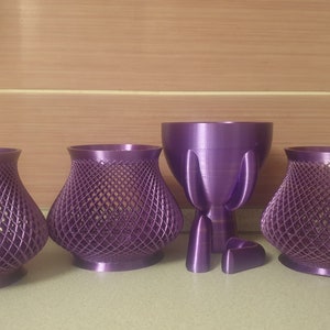 May include: Four purple 3D printed decorative objects. Three are vases with a lattice design and one is a tall, slender vase with a rounded base.