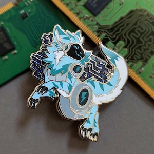 Könnte beinhalten: Detaillierter Emaille-Pin mit einem stilisierten, roboterhaften wolfsähnlichen Wesen in Blau-, Weiß- und Grautönen. Das Design umfasst Leiterplattenelemente und ein Blitzsymbol. Der Pin ist vor einem verschwommenen Hintergrund einer grünen Leiterplatte platziert.