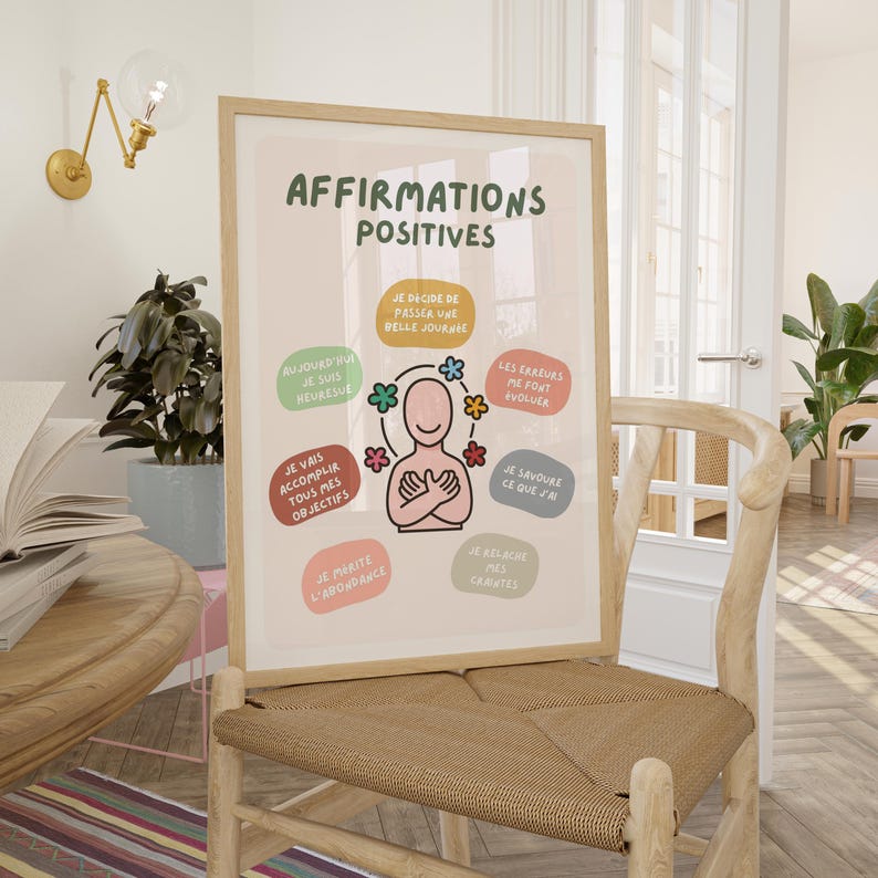 May include: A framed poster with the text "AFFIRMATIONS POSITIVES" in green. The poster features a cartoon figure surrounded by colorful affirmations in French. The poster is displayed on a wooden chair.
