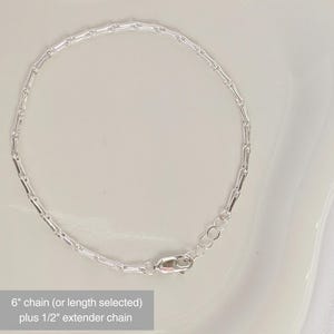 Puede incluir: Un brazalete de cadena de plata con cierre de langosta. La cadena mide 15,24 cm de largo con una cadena extensora de 1,27 cm.