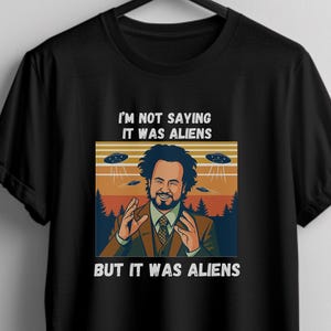 May include: Black t-shirt featuring a meme graphic with the text "I'M NOT SAYING IT WAS ALIENS BUT IT WAS ALIENS." The graphic includes an illustration of a man and flying saucers.
