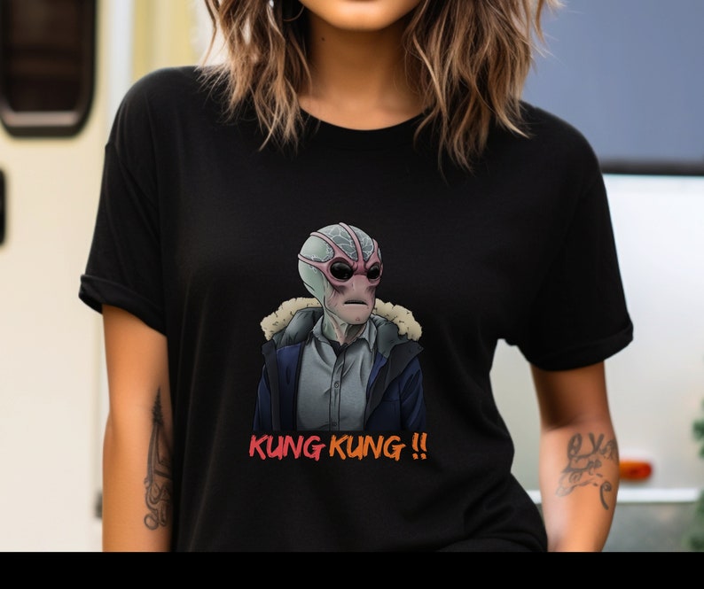 May include: Black t-shirt with a graphic of a pink and blue alien wearing a gray jacket and the text "KUNG KUNG!!" in orange.