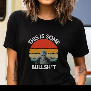 May include: Black t-shirt with a vintage-style graphic of a blue alien with the text "This is some Bullsh*t".