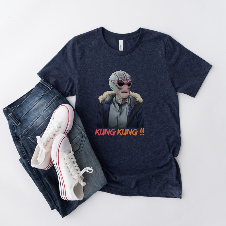 May include: A navy blue t-shirt with a graphic of a creature from the movie "The Shape of Water" wearing a jacket and the text "Kung Kung!!" printed in orange and red.