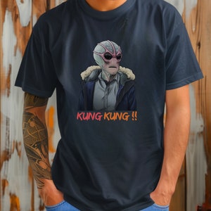 May include: A dark blue t-shirt with a graphic print of a gray alien wearing a winter coat and sunglasses. The text "KUNG KUNG!!" is printed in orange and red below the alien.