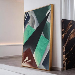 Può includere: Dipinto geometrico astratto in una cornice dorata. L'opera presenta una composizione di forme in verde, nero, grigio e marrone. Il dipinto è appoggiato a una parete bianca, mostrando uno stile d'arte moderno.