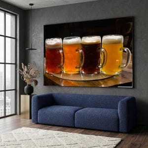 May include: A large framed print featuring four beer steins filled with different types of beer. The beers range in color from light amber to dark brown, each topped with a foamy head. The steins are on a wooden table.