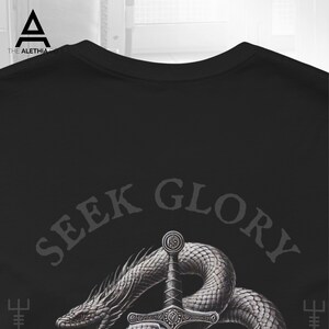 May include: Black t-shirt featuring a detailed illustration of a sword piercing through a coiled serpent. The text "SEEK GLORY" is arched above the sword and snake design. The shirt has a crew neck.