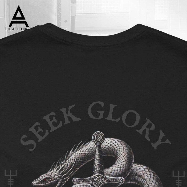 May include: Black t-shirt featuring a detailed illustration of a sword piercing through a coiled serpent. The text "SEEK GLORY" is arched above the sword and snake design. The shirt has a crew neck.