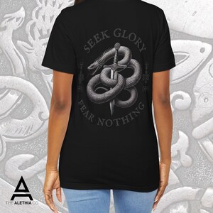 May include: Black t-shirt featuring a detailed graphic of a snake coiled around a sword, with the words "SEEK GLORY FEAR NOTHING" in a circular design. The shirt has a crew neck and short sleeves.