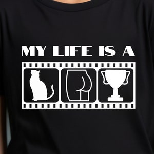 May include: Black t-shirt with white text that reads "My life is a" and a film strip with three images: a cat, a rear view of a person, and a trophy cup.