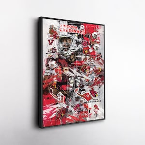 May include: Framed art print featuring a collage of Arizona Cardinals football players in action. The artwork is predominantly red, white, and black, with the team's logo and the words "Arizona Cardinals" prominently displayed. The print is mounted in a black frame.