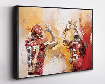 May include: Abstract art print of two football players in red and white uniforms, celebrating a play. The artwork features bold brushstrokes in shades of red, yellow, and white, with the players' jerseys displaying the numbers 87 and 15.