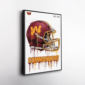 May include: A framed wall art print featuring a burgundy and gold football helmet with a W logo. The design includes paint drip effects in burgundy and gold, the text COMMANDERS, and the text EST. 1932 in the upper right corner on a white background.