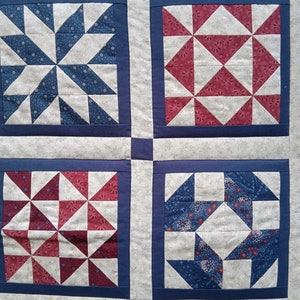 May include: A quilt with a patchwork design featuring red, white and blue squares. Each square has a different pattern of triangles.