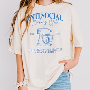 Pu&ograve; includere: Una tazza di ceramica bianca con manico nero e la scritta "But First, Coffee" in grassetto nero. La tazza &egrave; posta su uno sfondo sfocato, che suggerisce un'atmosfera accogliente.