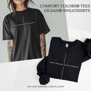May include: Black t-shirt and sweatshirt with the text "CROSS TRAINING BUILDS STRENGTH" and a vertical white line. The t-shirt is short-sleeved, and the sweatshirt is long-sleeved. The text "COMFORT COLORS TEES" and "GILDAN SWEATSHIRTS" are at the top.