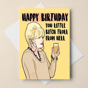 May include: A humorous birthday card featuring a cartoon illustration of a woman with the text "HAPPY BIRTHDAY YOU LITTLE BITCH TROLL FROM HELL". The card is on a yellow background.