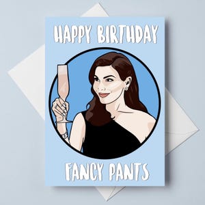 Peut inclure: Carte d'anniversaire bleu clair avec les mots "Happy Birthday" et "Fancy Pants" en blanc. La carte présente une illustration de femme tenant une coupe de champagne.