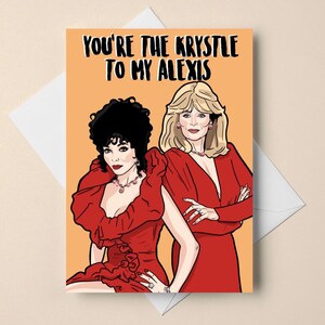 Könnte beinhalten: Grußkarte mit dem Text "You're the Krystle to my Alexis" über einer Illustration von zwei Frauen in roten Kleidern. Eine Frau hat dunkles Haar, die andere blondes Haar. Der Hintergrund ist orange.