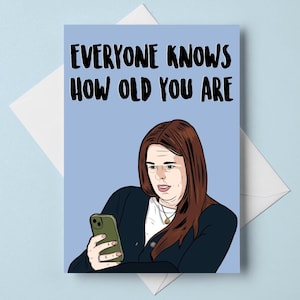 Può includere: Un biglietto di auguri con la scritta "EVERYONE KNOWS HOW OLD YOU ARE" in nero. Il biglietto presenta un'illustrazione di una donna che guarda il suo telefono. Lo sfondo è azzurro e il biglietto è dentro una busta bianca.