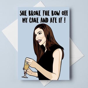 Peut inclure: Une carte de vœux sur fond bleu clair avec une illustration dessinée d'une personne aux longs cheveux bruns portant un haut noir et tenant une flûte à champagne. Le texte indique : SHE BROKE THE BOW OFF MY CAKE AND ATE IT !