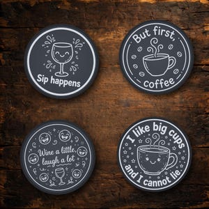 May include: Four circular dark gray coasters with white line art designs. One features a wine glass and the text "Sip happens". Another shows a coffee cup with "But first, coffee". A third displays emojis and "Wine a little, laugh a lot". The fourth shows a coffee cup and "I like big cups and I cannot lie".