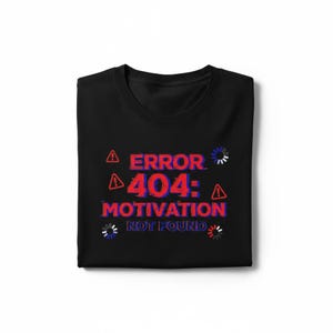 Könnte beinhalten: Schwarzes T-Shirt mit dem Text "ERROR 404: MOTIVATION NOT FOUND" in Rot und Blau. Das Design beinhaltet Warnsymbole und Lade-Icons. Das T-Shirt ist gefaltet.