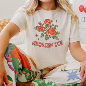 Ivory cropped Comfort Colors tee with floral message worn by woman in colorful printed pants