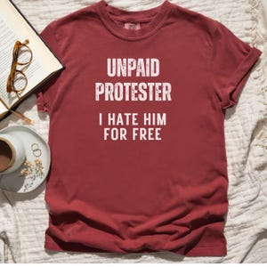Flat lay of crimson red Comfort Colors protest tee styled with tea, glasses, and a book.