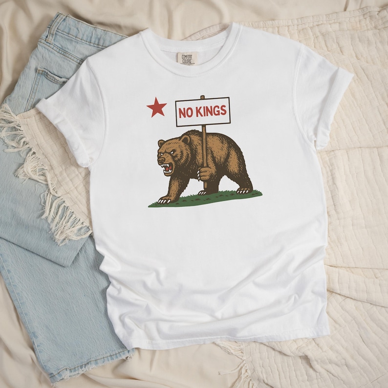 White Comfort Colors tee flatlay with California resistance bear and NO KINGS sign graphic.