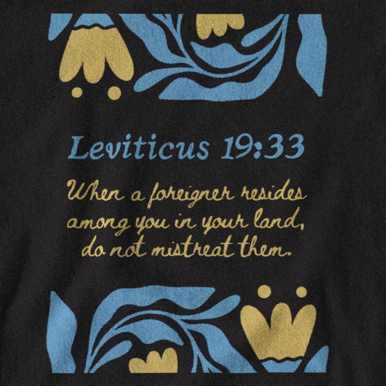 May include: Black t-shirt with the text "Leviticus 19:33" and a quote about treating foreigners with kindness. The design includes blue and gold floral accents at the top and bottom.