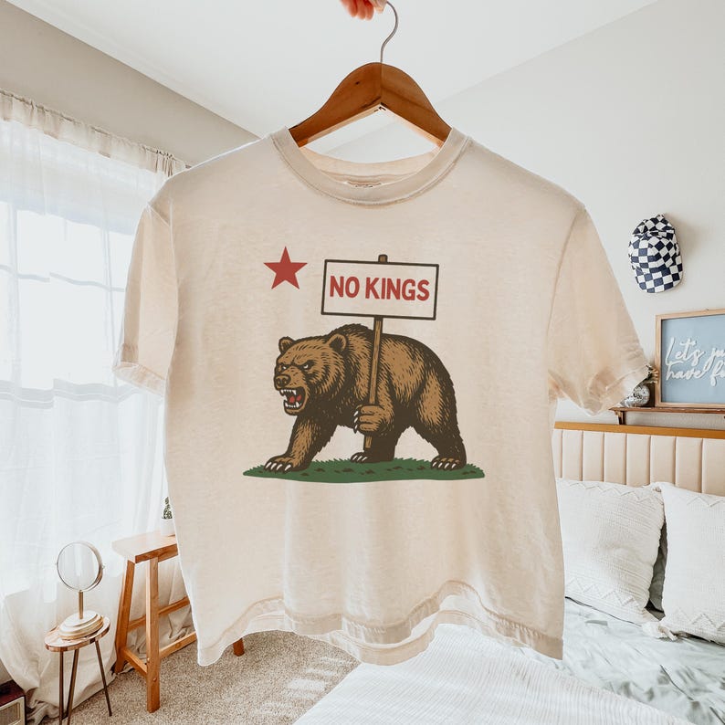 Natural cropped Comfort Colors t-shirt on hanger in bedroom, California resist bear protest graphic.