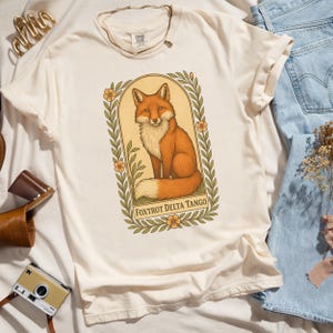 Neutral cream Foxtrot Delta Tango Comfort Colors shirt, illustrated fox graphic, soft political protest apparel for activists.