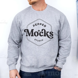 Könnte beinhalten: Ein graues Sweatshirt mit einem schwarzen Logo, auf dem "Pepper Mocks Studio" in einer Retro-Schrift steht.