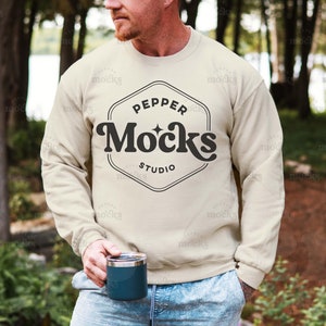 Pode incluir: Uma camisa de moletom bege com um logotipo preto que diz "Pepper Mocks Studio" em uma fonte retrô.