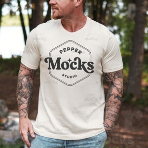 Può includere: Una maglietta bianca con un logo nero che dice "Pepper Mocks Studio" in un font retrò.