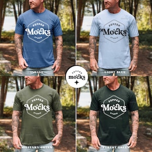 May include: Four short-sleeved t-shirts in indigo, light blue, military green, and forest green. Each shirt features a white hexagonal logo with the text "PEPPER Mocks STUDIO". The shirts are displayed on a person.