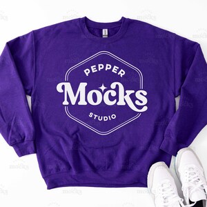 May include: Purple sweatshirt with long sleeves and a white logo that says "Pepper Mocks Studio" in a retro font.
