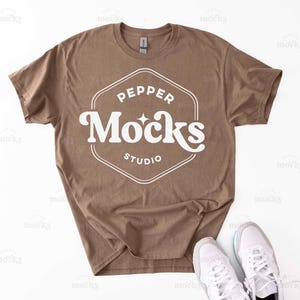 Könnte beinhalten: Ein braunes T-Shirt mit einem weißen Grafikdesign, auf dem "Pepper Mocks Studio" steht.