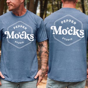 Può includere: T-shirt blu a maniche corte con la scritta "Pepper Mocks Studio" in un design bianco in stile retrò sul davanti e sul retro. La maglietta ha uno scollo tondo e un aspetto leggermente sbiadito.