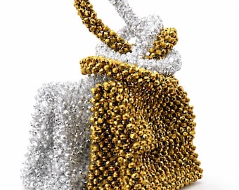 May include: A handbag constructed from small, faceted beads in metallic gold and silver. The bag features a structured, rectangular body with a top handle formed by a loop of silver beads, creating a two-tone, textured, and reflective appearance.