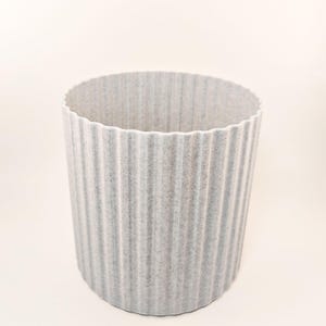 May include: A gray, ribbed, cylindrical planter made of a textured material.