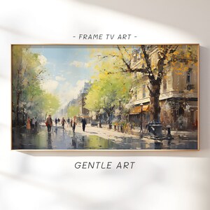 Puede incluir: Una pintura que representa una escena de calle de ciudad con personas caminando por una calle adoquinada mojada. Los edificios están en el fondo y hay árboles a ambos lados de la calle. El cielo es azul con nubes blancas. La pintura está enmarcada.
