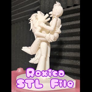 May include: A white 3D printed figurine of two cartoon characters, a wolf and a bird, embracing. The base of the figurine is a heart shape with the text "Roxico STL File" in pink letters.
