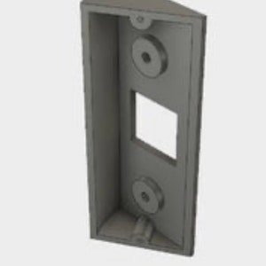 May include: A gray plastic wall mount with two round holes and a rectangular opening. The mount is designed to hold a doorbell or other device.
