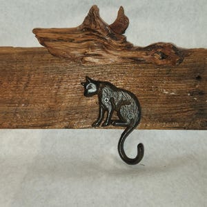May include: A rustic wooden wall-mounted coat rack with three hooks shaped like cats. The rack is made from reclaimed wood and has a natural, weathered finish.
