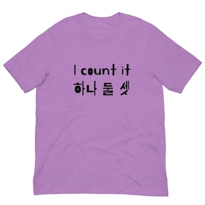 Peut inclure: T-shirt lilas avec l'inscription noire "I count it", suivie de caractères coréens. Ce t-shirt à manches courtes est fabriqué dans une matière douce, parfait pour un usage quotidien.