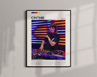 May include: Framed poster featuring the name "CINTHIE" with "Berlin" below. The image shows a person operating DJ equipment with a colorful neon light backdrop. The poster has a black frame and includes text at the bottom.