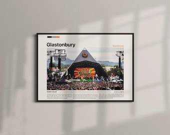 May include: Framed poster featuring the Glastonbury music festival stage. The image shows a large crowd in front of a pyramid-shaped stage with a colorful display. The poster includes the text "Glastonbury" and "Somerset".